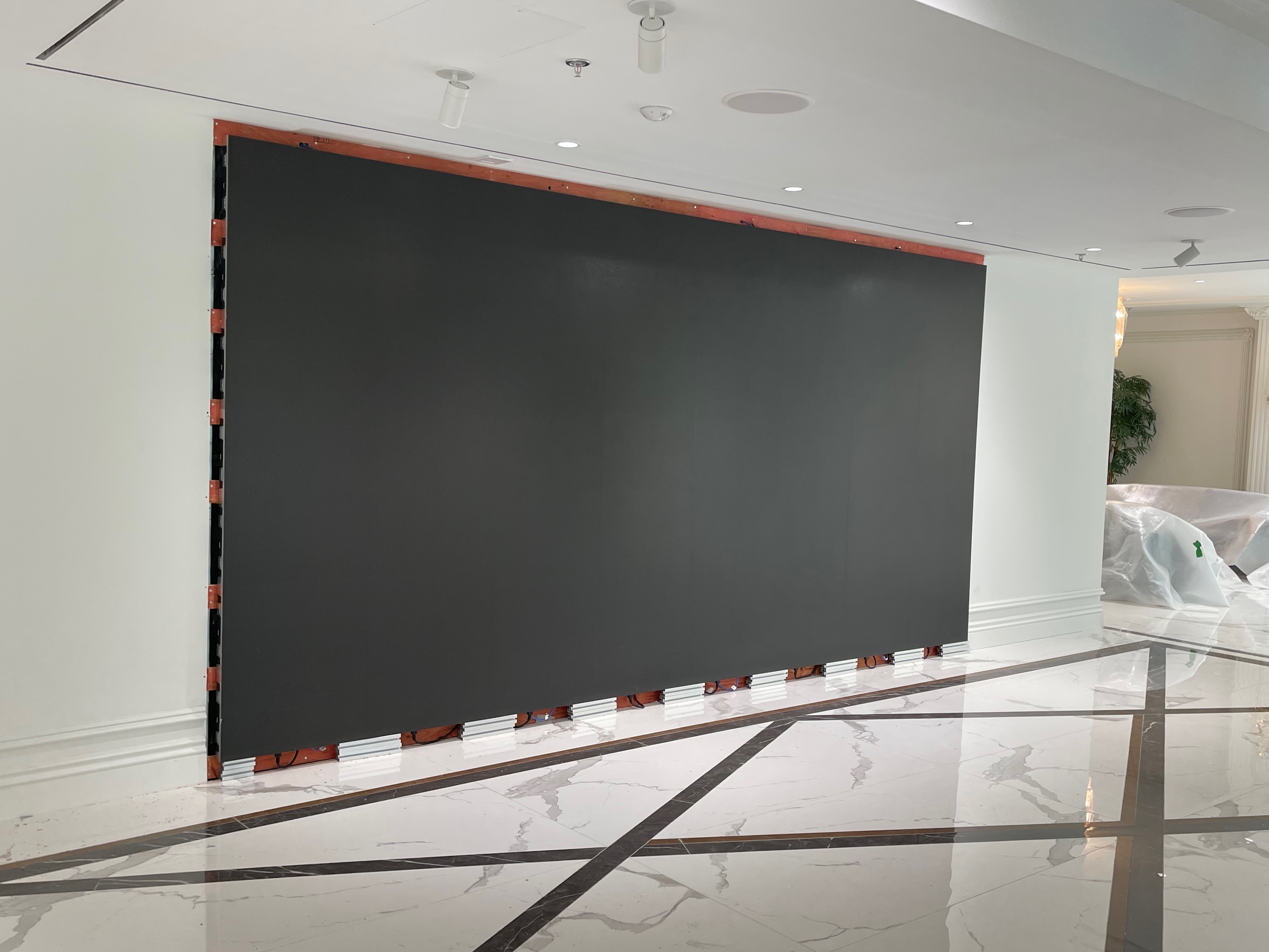 Finished fine pitch LED wall powered off — one continuous matte black surface with no visible seams, trimmed flush into the wall