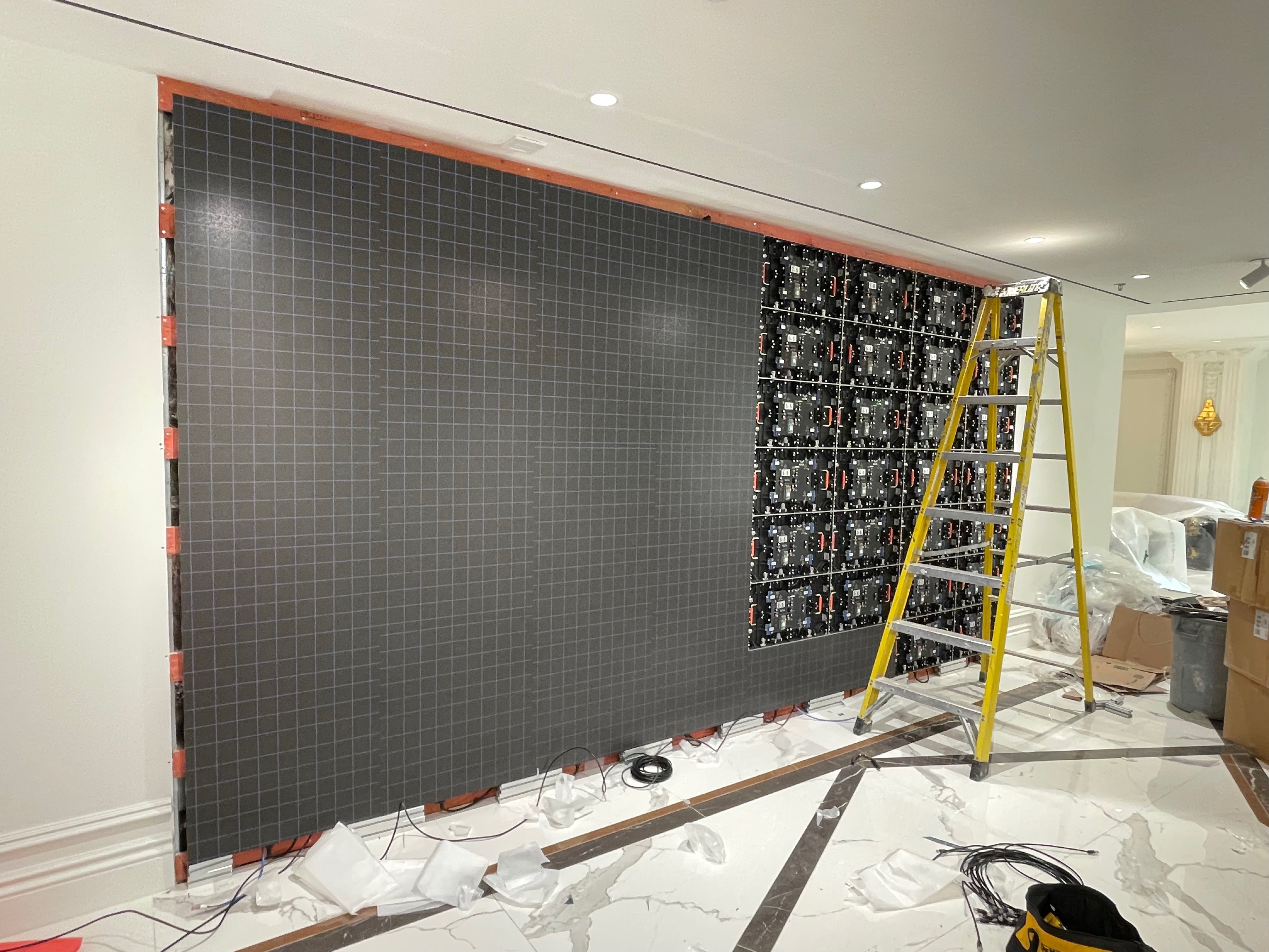 Fine pitch LED wall part-way through installation, left half faced with cabinets and right half showing the open frame