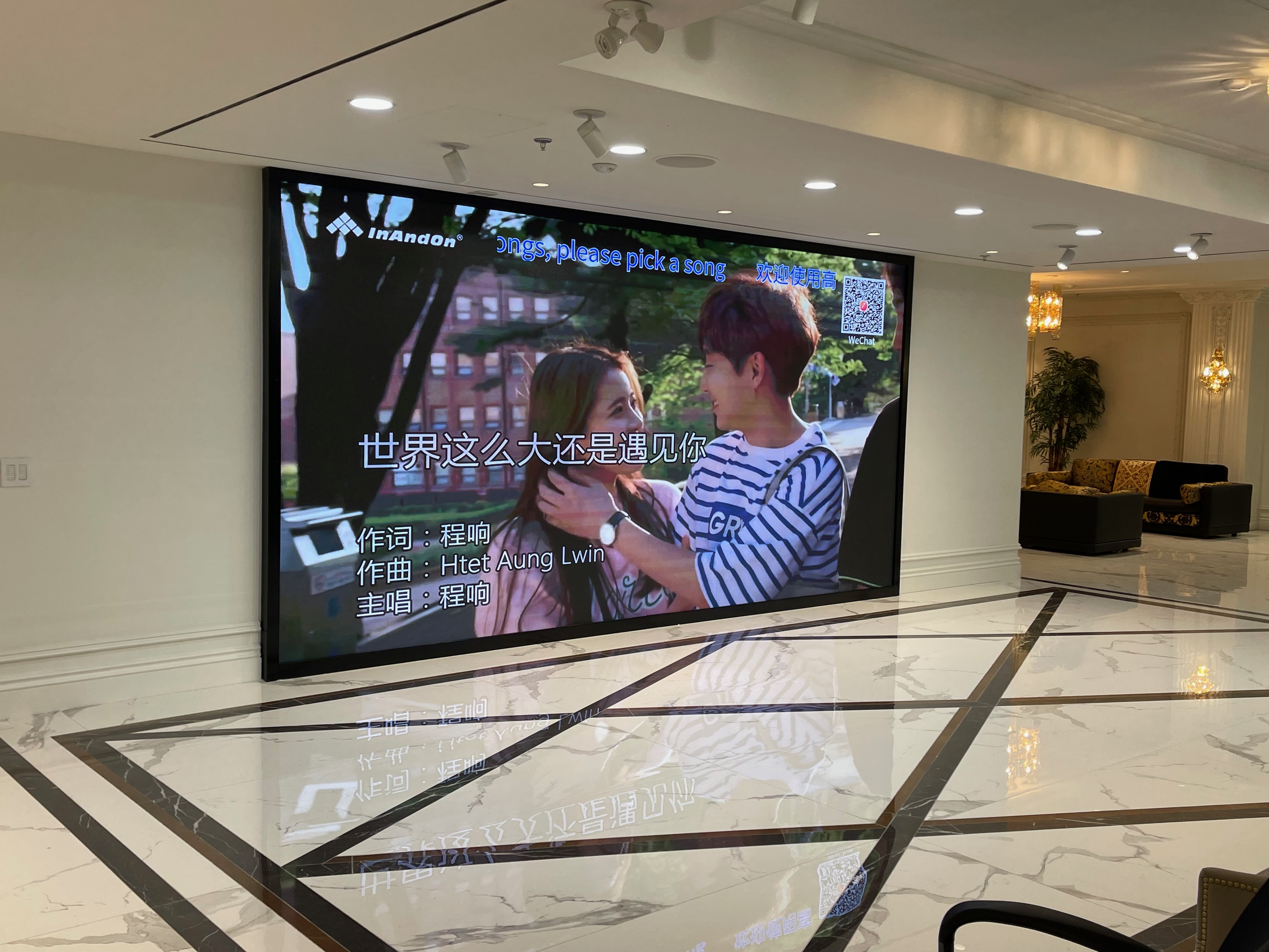 The installed lobby LED wall playing video with on-screen text and graphics, seen from an angle across a marble floor