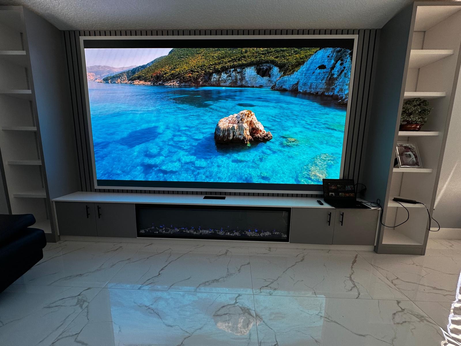 Fine pitch COB LED screen built into a home theatre feature wall with slatted acoustic panels, a media credenza and a linear fireplace below