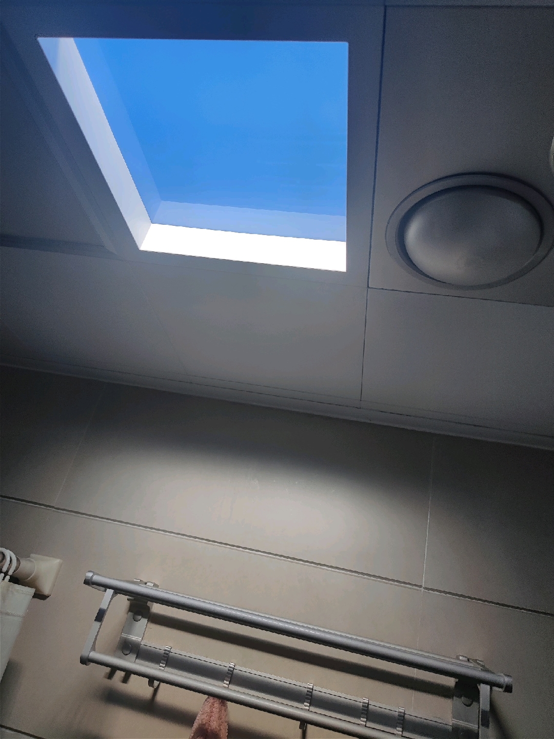 Close angled view of an LED skylight panel showing deep blue sky in the field and bright white light at the frame edge